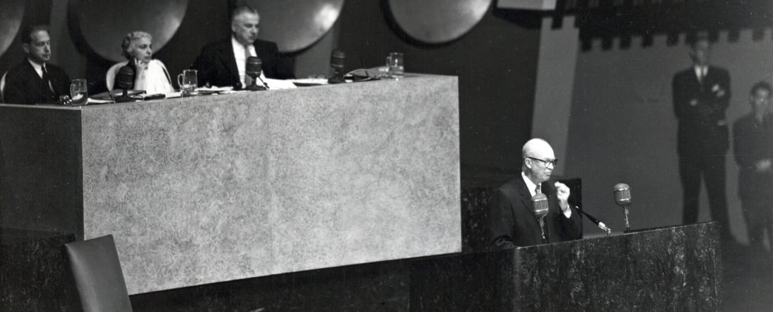 Historical black and white photo of a speaker and panelists