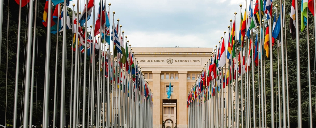 Row of flags at entrance of United Nations Offices or Palais des Nations in Ariana Park, on shore of Lake Geneva in Geneva, Switzerland. Since 1966 is main European headquarters of UN.